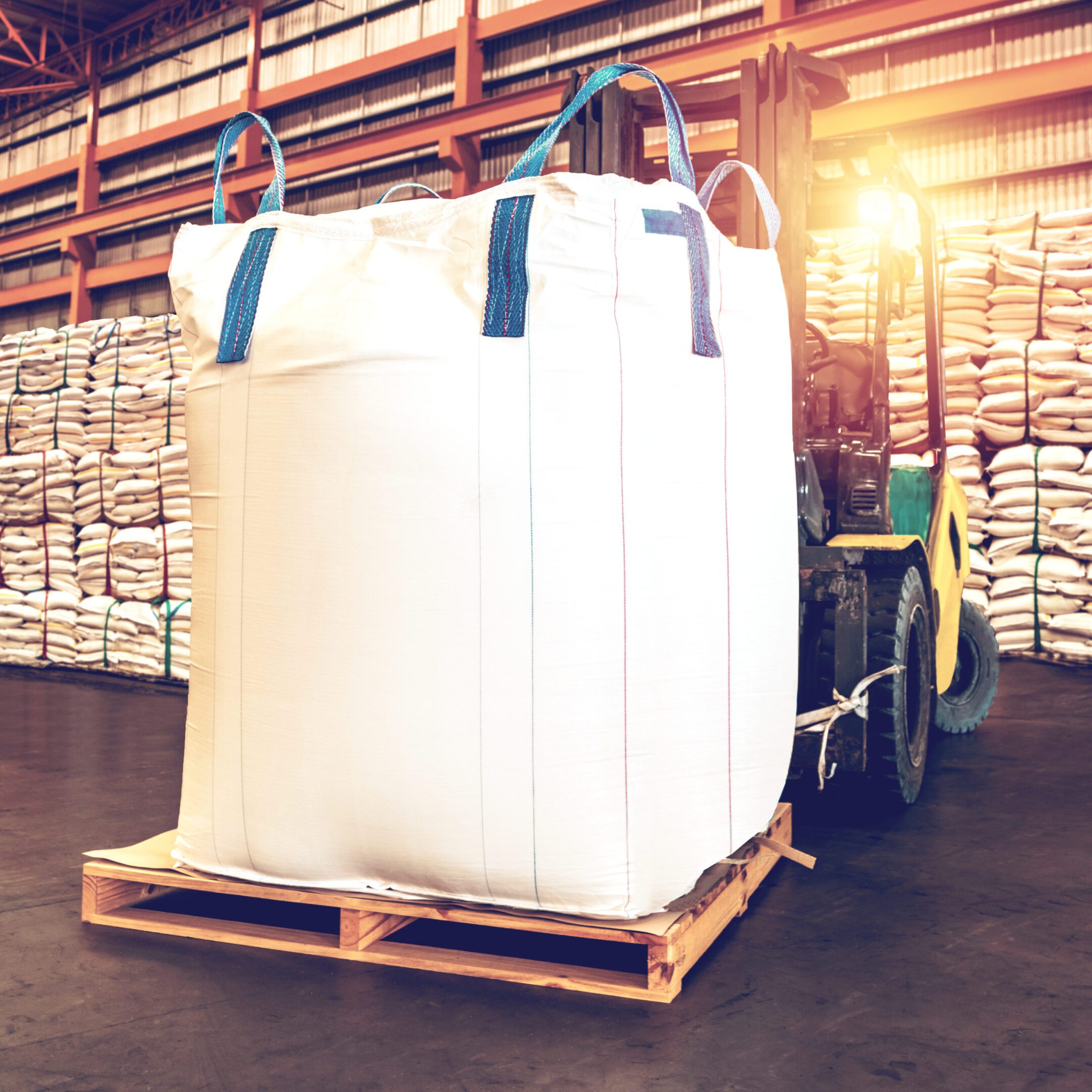 A forklift carrying bags of white powder in a warehouse.